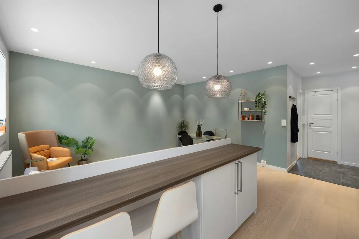 A calm reception area with soft green walls and wooden seating