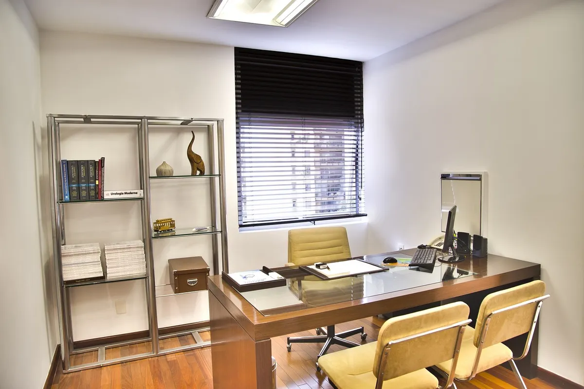 A bright consultation room with a desk and two chairs