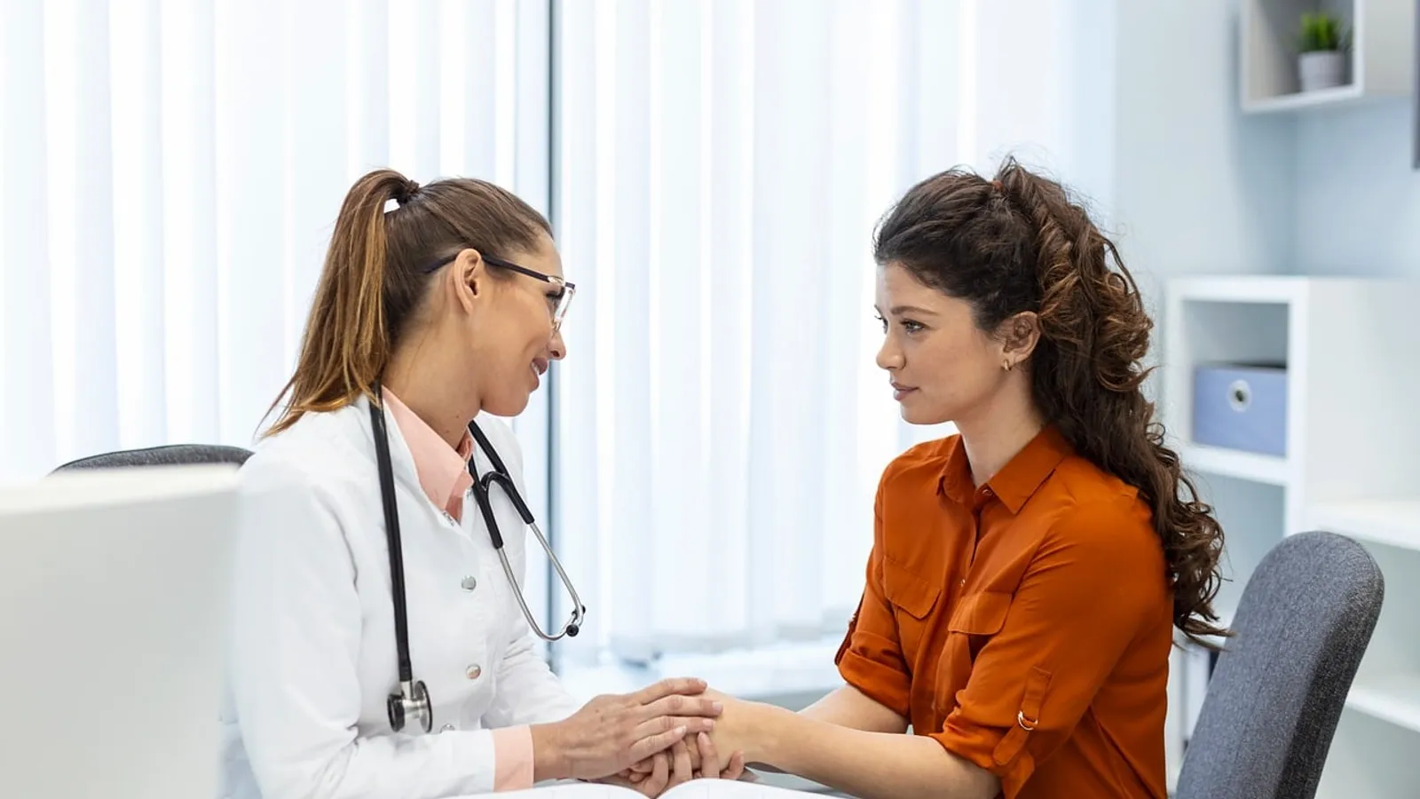 A doctor talking with a couple in a bright consultation room